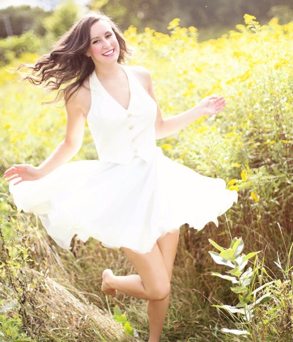 Smiling woman stretching gently in a bright, sunlit room, representing vitality.